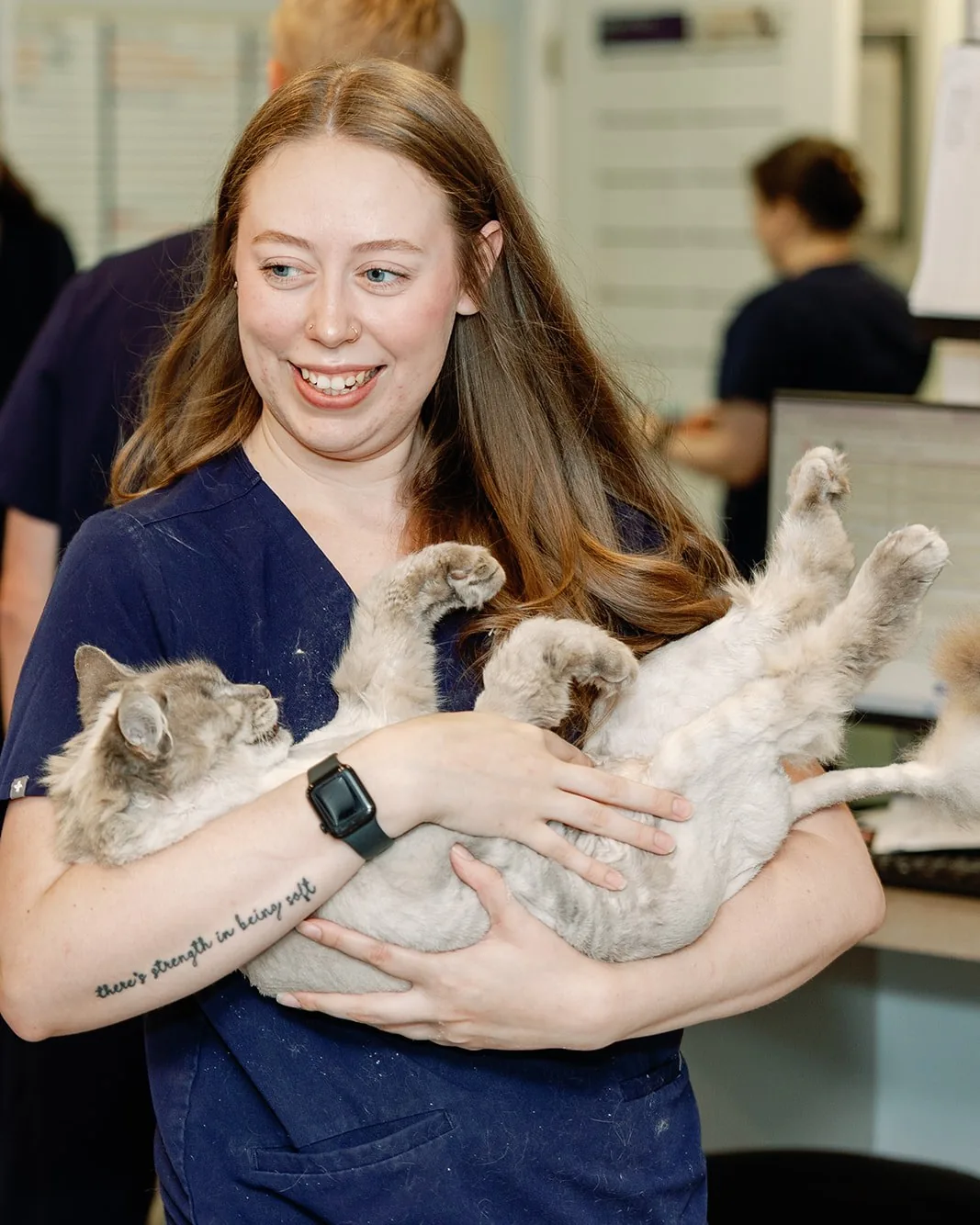 A Noah's Ark technician cradling a relaxed cat in her arms