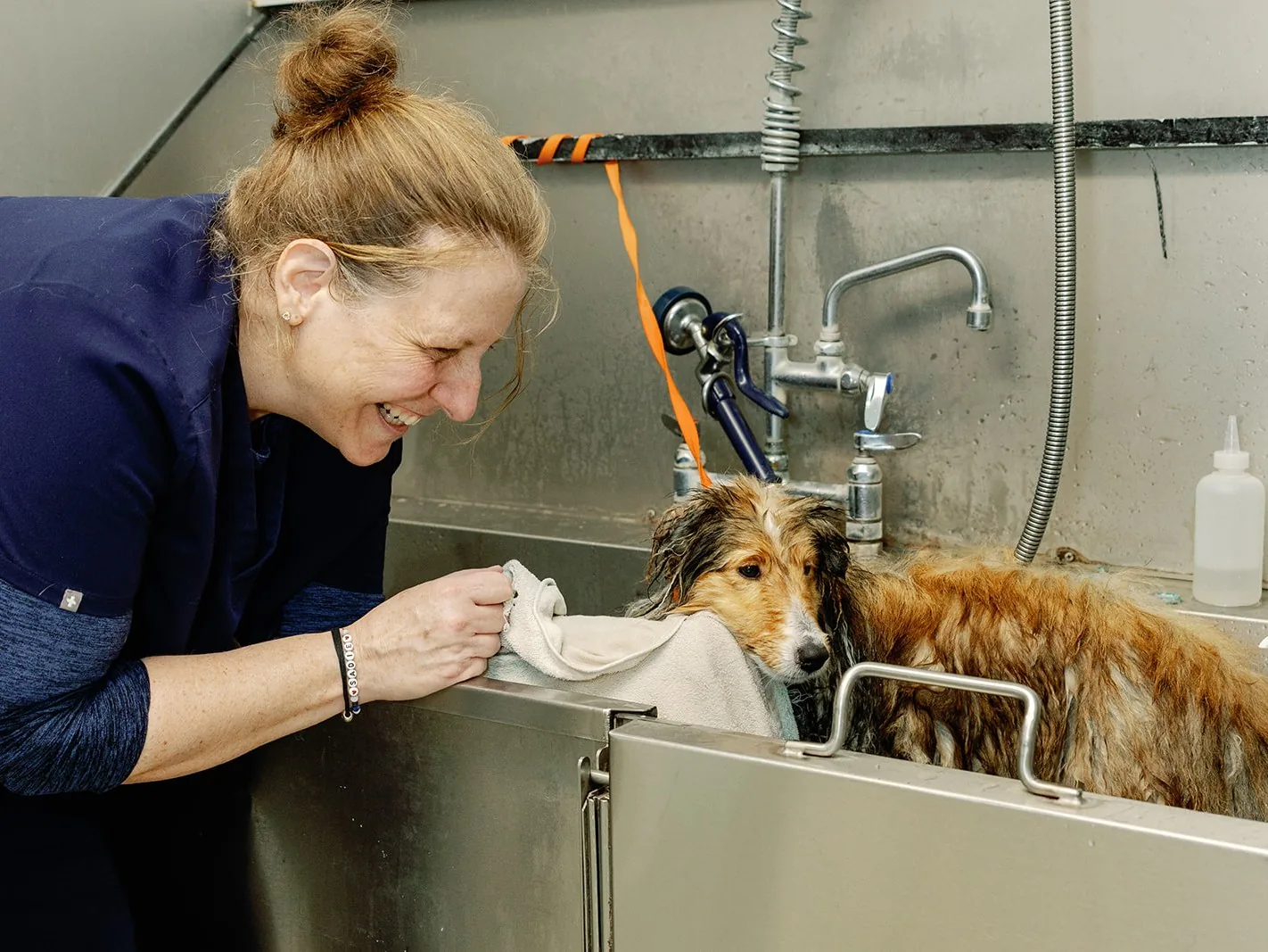 A Noah’s Ark team member laughing face to face with a dog after a bath